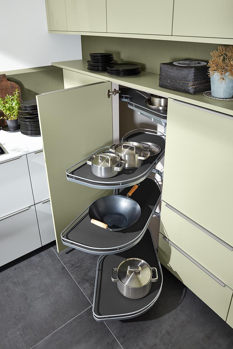 Hellgrüner Küchenschrank mit ausfahrbaren grauen Tablaren für Töpfe und Pfannen.