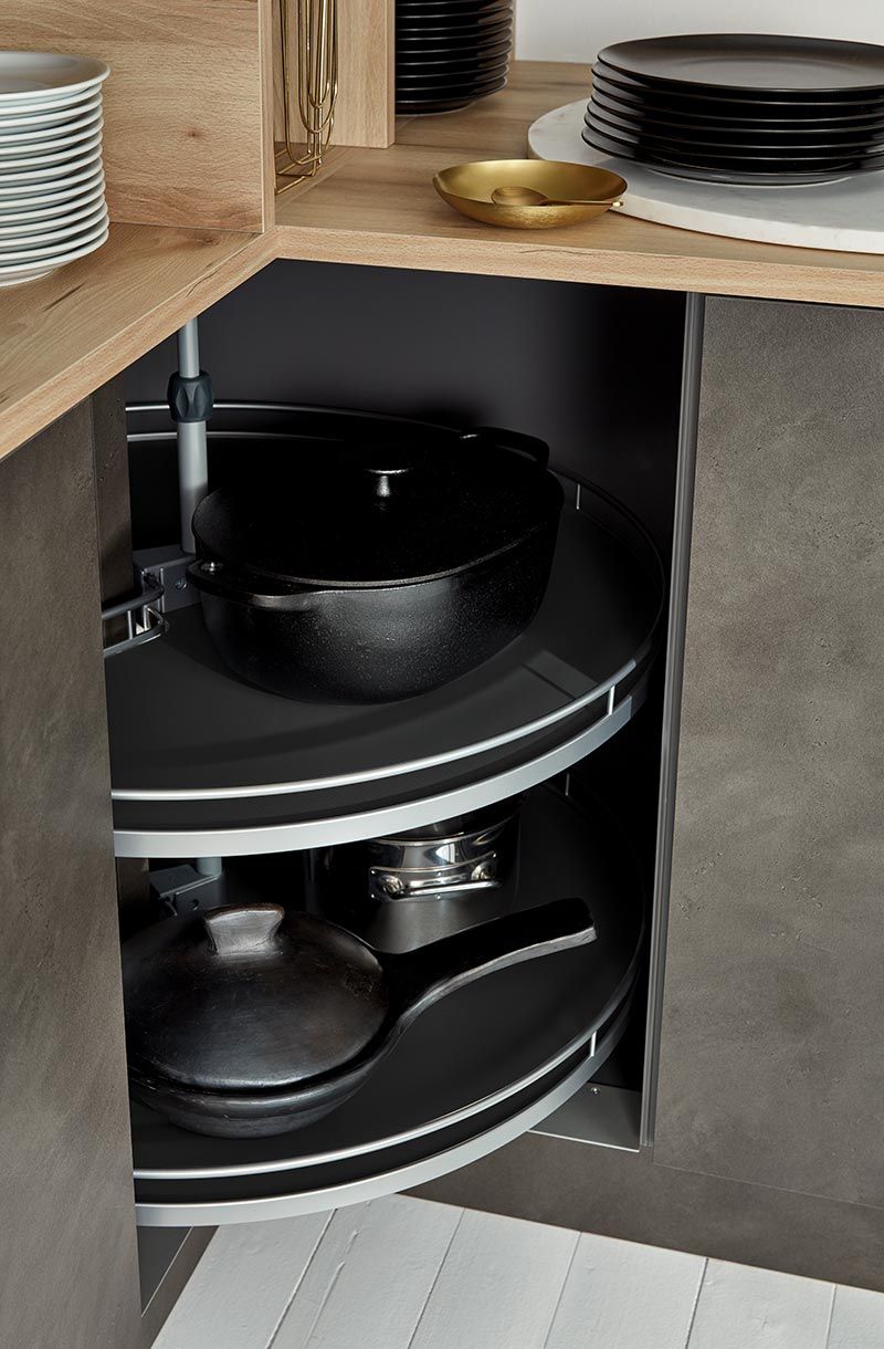 Drehbarer Eckschrank-Auszug mit schwarzen Töpfen und Pfannen in moderner Küche.