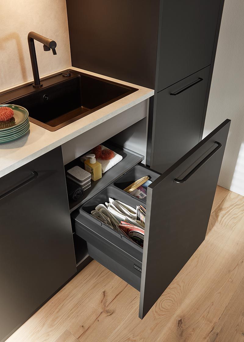 Ausziehbarer schwarzer Unterschrank mit integrierten Abfalleimern zur Mülltrennung.