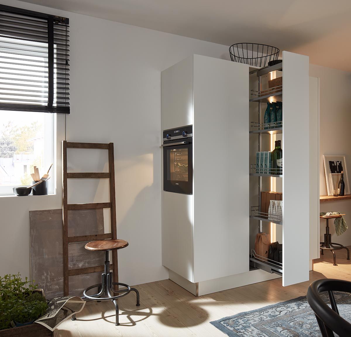 Weißer Küchenhochschrank mit ausziehbarem Vorratsregal neben einem integrierten Backofen.