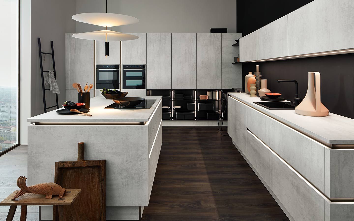 Helle Küche in Beton-Optik mit Kochinsel und dunklem Holzboden.