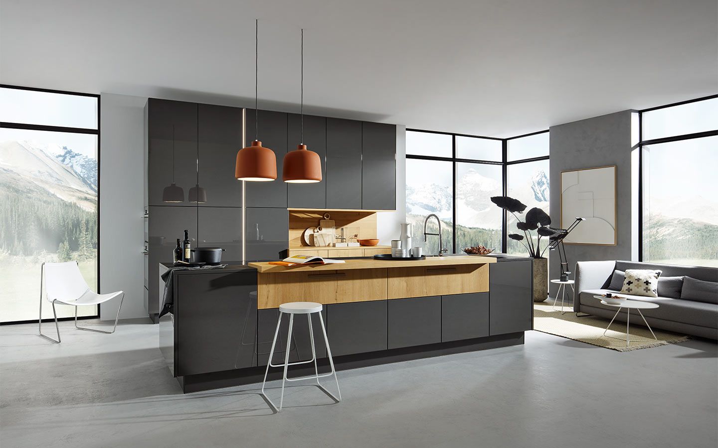 Graue Kochinsel mit Holztheke unter drei terracottafarbenen Pendelleuchten vor Bergpanorama.