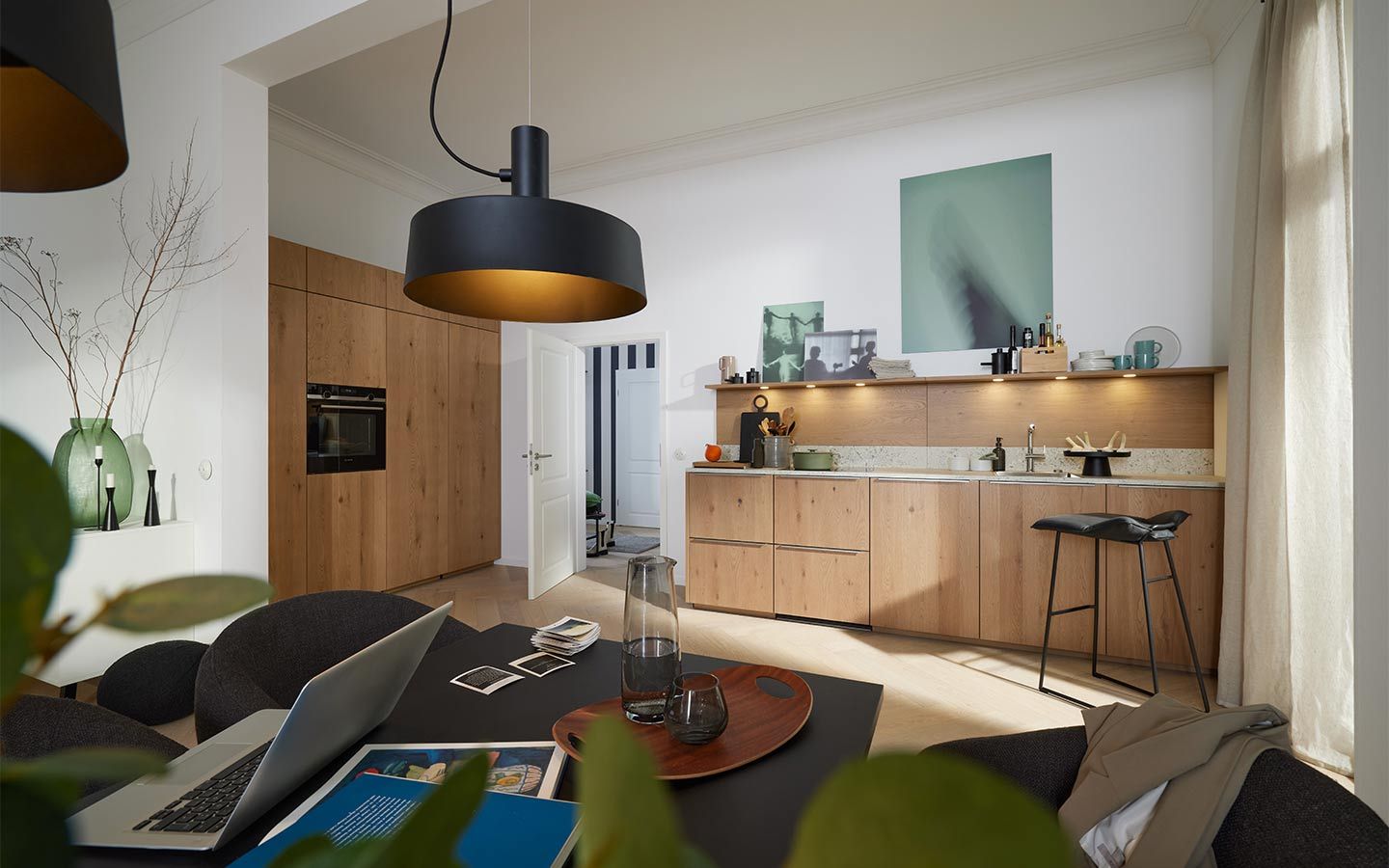 Helle Eichenküche mit schwarzer Lampe und Arbeitsbereich im Vordergrund.