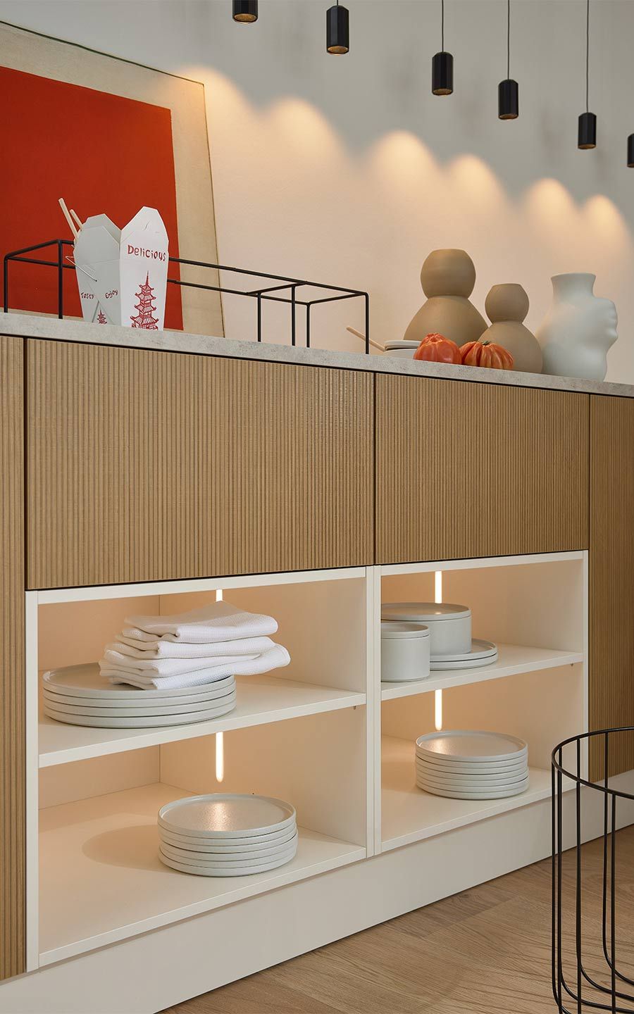 Offenes weißes Regal mit Geschirr unter geriffelten Holzfronten.