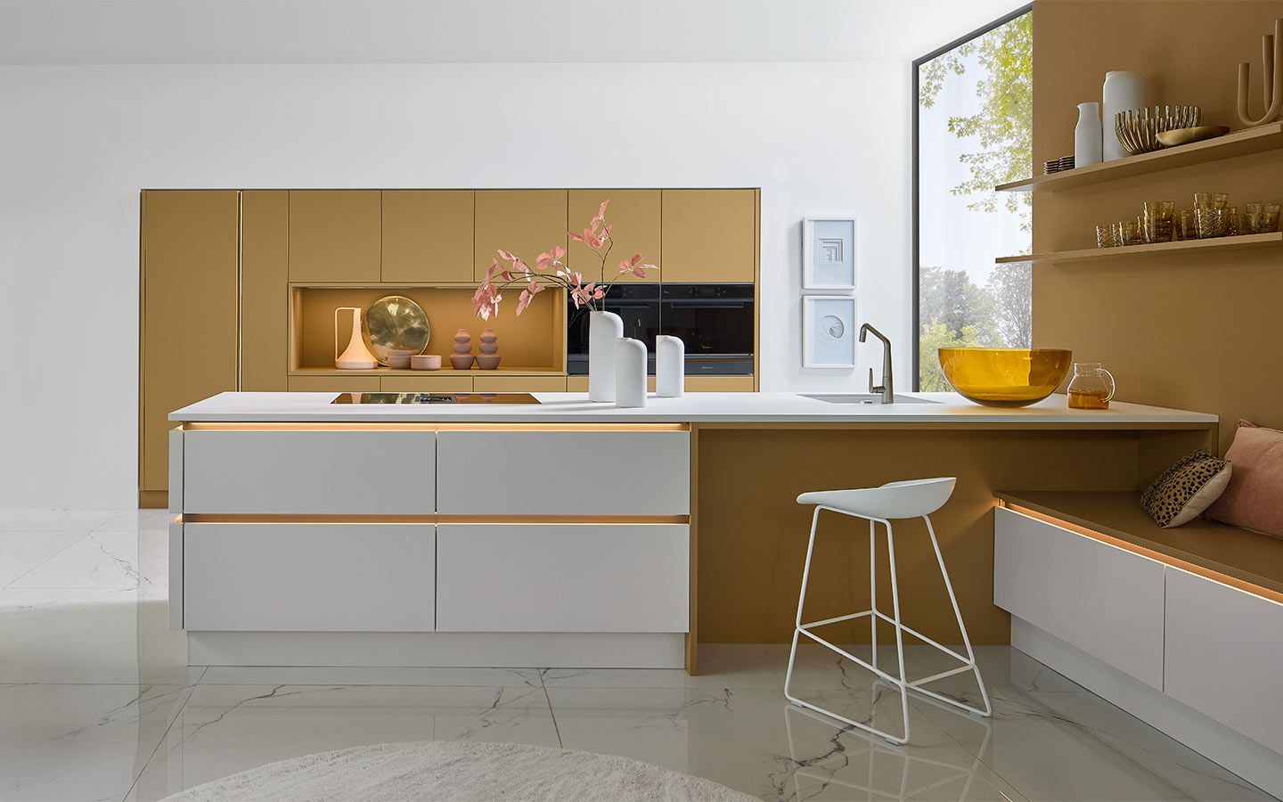 Weiße Kochinsel vor ockerfarbener Schrankwand mit integrierter Sitzbank und Marmorboden.