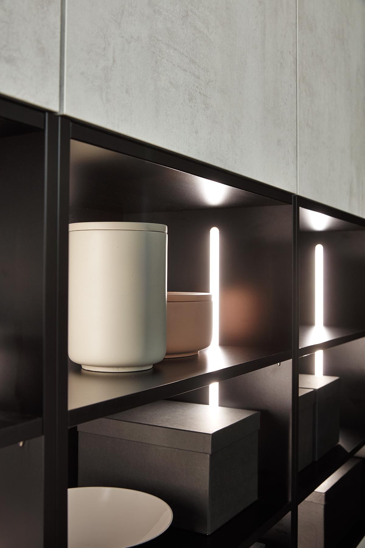 Detailaufnahme eines schwarzen Regals mit Lichtleisten, Vorratsdosen und Boxen.